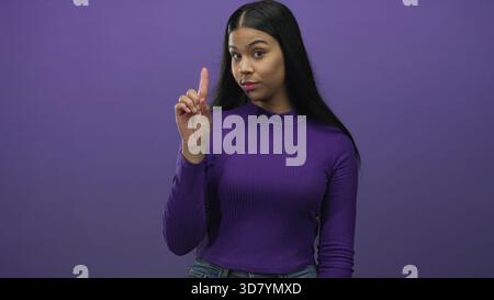 Jeune femme latine debout centrée compte ses doigts de un à trois dans un studio violet ; ordre séquence Focus progression. Banque D'Images