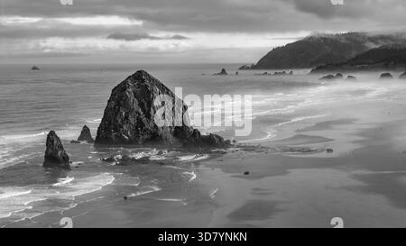 Prise aérienne au-dessus de Cannon Beach, Oregon, par un matin brumeux, avec Haystack Rock et des paysages côtiers moroses Banque D'Images