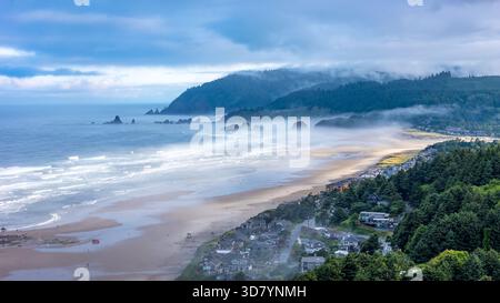 Prise aérienne au-dessus de Cannon Beach, Oregon, par un matin brumeux, avec Haystack Rock et des paysages côtiers moroses Banque D'Images