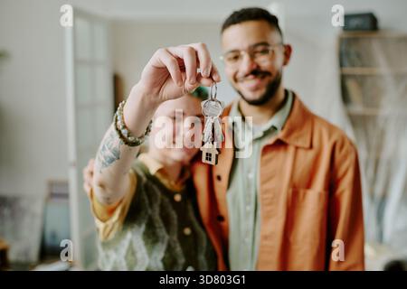Jeune couple tenant Keys souriant tout en emménageant dans la nouvelle maison Banque D'Images