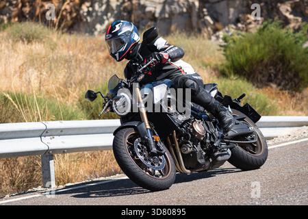 Motocycliste prenant un virage serré par un dimanche ensoleillé dans le port de Navalmoral, dans la province d'Avila, en Espagne, au cours du mois d'août 2023 Banque D'Images