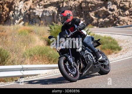 Motocycliste prenant un virage serré par un dimanche ensoleillé dans le port de Navalmoral, dans la province d'Avila, en Espagne, au cours du mois d'août 2023 Banque D'Images