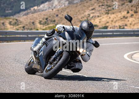 Motocycliste prenant un virage serré par un dimanche ensoleillé dans le port de Navalmoral, dans la province d'Avila, en Espagne, au cours du mois d'août 2023 Banque D'Images