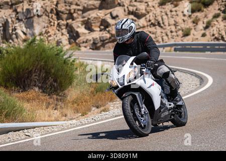 Motocycliste prenant un virage serré par un dimanche ensoleillé dans le port de Navalmoral, dans la province d'Avila, en Espagne, au cours du mois d'août 2023 Banque D'Images