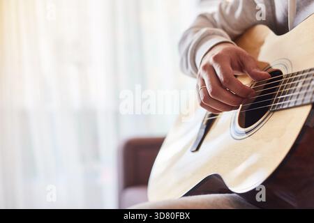 Plan recadré d'un homme pratiquant à jouer de la guitare acoustique. Gros plan d'un homme jouant de la guitare. Banque D'Images