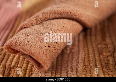 Un morceau roulé d'injera, le pain plat éthiopien fait de teff, une farine de spécialité locale Banque D'Images