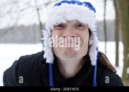 Homme drôle fou avec chapeau d'hiver bleu faisant un visage drôle Banque D'Images