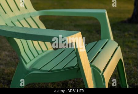 Une personne assise dans l'une des quatre chaises adirondack, surplombant le lac au coucher du soleil par temps clair. Silhouette de chaises et d'arbres. Banque D'Images
