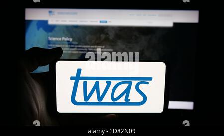 Dans cette illustration photo, une personne tient un téléphone portable avec le logo de l'Académie mondiale des sciences (TWAS) sur l'écran devant la page Web. Banque D'Images