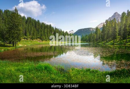 Vue sur le Lago di Antorno, un lac de montagne dans les Dolomites, Vénétie, Italie, reflétant la forêt environnante et les sommets lointains et déchiquetés du Tre C. Banque D'Images