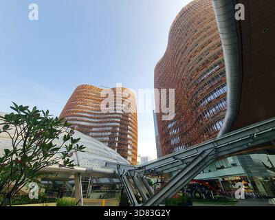 Deux tours courbes modernes avec une façade orange unique et une structure blanche futuriste en dessous, mettant en valeur l'architecture urbaine contemporaine. Banque D'Images