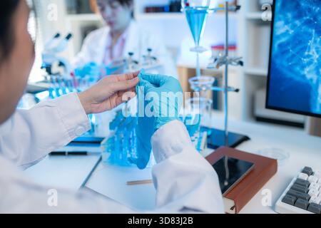 Un intérieur de laboratoire scientifique moderne avec de la verrerie organisée, des tubes à essai remplis de liquide bleu et des équipements de recherche avancés sur un blanc propre Banque D'Images