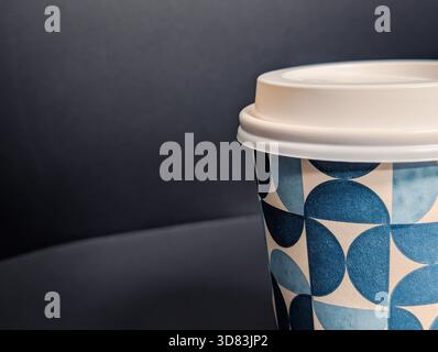 Gros plan macro extrême d'une tasse à café jetable avec motif géométrique bleu et couvercle blanc Banque D'Images