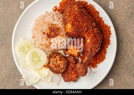 Ayam Goreng Kremes ou poulet frit indonésien servi avec une garniture de kremes croustillante sur une assiette, avec une texture brun doré et des miettes croustillantes Banque D'Images