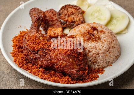 Ayam Goreng Kremes ou poulet frit indonésien servi avec une garniture de kremes croustillante sur une assiette, avec une texture brun doré et des miettes croustillantes Banque D'Images