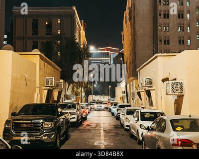 Ruelle étroite la nuit à Doha, Qatar, avec des immeubles résidentiels beiges, des voitures garées Banque D'Images