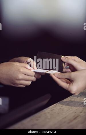 Deux mains échangent une carte de visite et des transactions, mettant en évidence le réseautage, le contact professionnel et la collaboration entre les individus. ECHANGE personnel Banque D'Images
