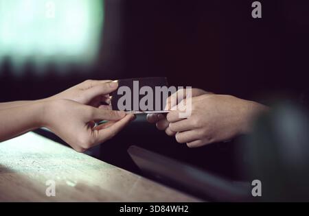 Deux mains échangent une carte de visite et des transactions, mettant en évidence le réseautage, le contact professionnel et la collaboration entre les individus. ECHANGE personnel Banque D'Images