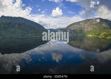 Vue aérienne des eaux sereines du fjord reflétant le ciel et les majestueuses montagnes verdoyantes, créant un paysage tranquille, Fjord, Norvège. Banque D'Images