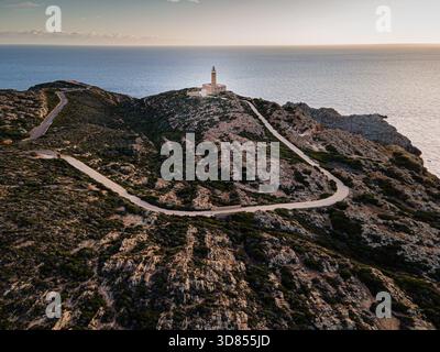 Vue aérienne d'un phare perché au sommet de falaises escarpées, embrassé par les teintes dorées du soleil couchant surplombant la mer, Capo Sandalo, San Pietro, sa Banque D'Images