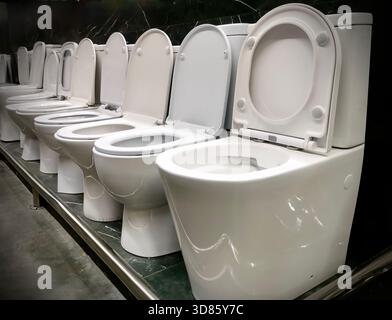 Toilettes modernes en céramique blanche exposées dans une salle d'exposition de magasin de plomberie. Intérieur minimaliste propre, adapté à la construction, la rénovation, la conception de salle de bains Banque D'Images