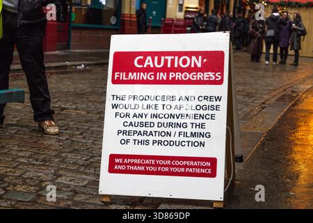 Attention tournage en cours panneau sur Urban Cobblestone Street Banque D'Images