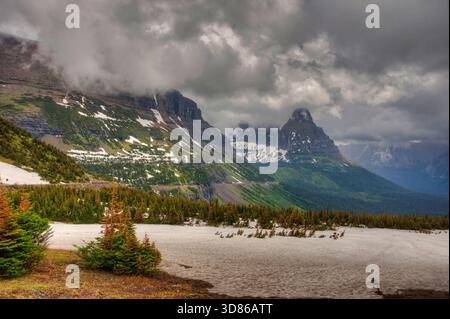 Vue sur la montagne sombre depuis Logan Pass dans le parc national des glaciers, avec la neige et les nuages lourds projetant une lumière étrange et changeante. Banque D'Images