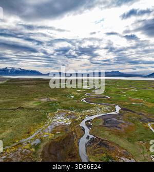 Vue aérienne d'une rivière serpentine serpentant à travers un paysage vert et brun vibrant sous un ciel spectaculaire, rivière Hvíta, Islande. Banque D'Images
