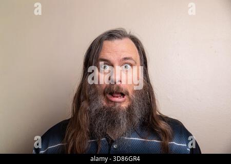 Un homme avec une barbe et de longs cheveux est couvert de neige Banque D'Images