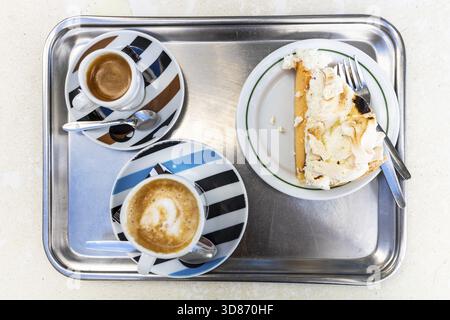Deux tasses de café et une tranche de gâteau sur un plateau en métal dans un café au Portugal Banque D'Images