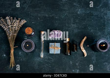 Arrangement mystique avec lavande, bougies, cristaux et huiles essentielles sur fond sombre. Vue de dessus, pose à plat. Banque D'Images