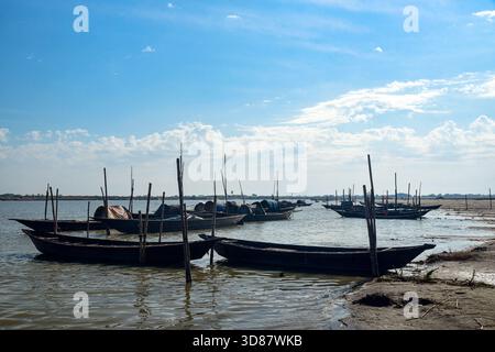 Bateaux de pêche amarrés le long de Shallow Shore Under Blue Sky sur les eaux de Calm River Banque D'Images
