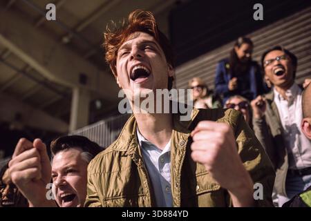 Vue à angle bas du jeune homme criant tout en regardant un match dans le stade depuis le stand Banque D'Images
