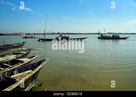 Scène de rivière tranquille avec bateaux en bois traditionnels et eau calme sous un ciel clair Banque D'Images
