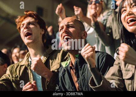 Vue à angle bas de l'homme chauve criant tout en acclamant avec les spectateurs dans le stade debout à la journée ensoleillée Banque D'Images