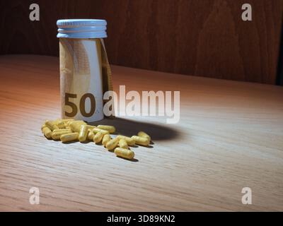 Coût de la médecine : Euro Banknote & Pills - cinquante billets de banque en euros roulés dans une bouteille à côté d'une pile de capsules médicales jaunes sur une table en bois, symbole Banque D'Images