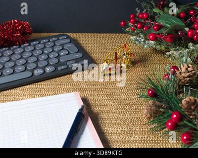 Station de travail festive Holiday - clavier moderne, lunettes et un ordinateur portable sur une surface dorée chatoyante avec des décorations rouges de vacances, suggérant festiv Banque D'Images
