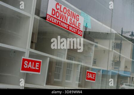 Fermeture des affiches de vente et des étagères vides dans une vitrine de grande rue. Videz les étagères de la grande rue après la fermeture. Banque D'Images