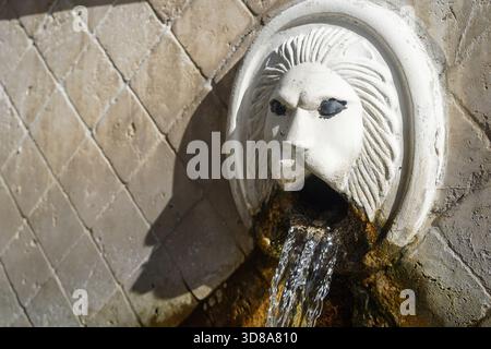 Des plans rapprochés montrent la tête de lion richement conçue de la fontaine Kefalovrysi à Spili, en Crète. L'eau de source cristalline en coule puissamment. Banque D'Images