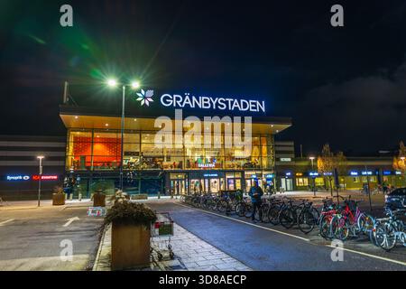 Belle vue sur le centre commercial Granbystaden illuminé la nuit avec des vélos garés près de l'entrée. Suède. Uppsala. Banque D'Images