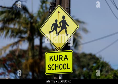 Un panneau de signalisation multilingue indiquant un passage d'enfants pour une école à côté du mot école et kura à Auckland, Nouvelle-Zélande Banque D'Images