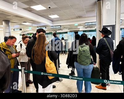 Dublin, Irlande - 21 octobre 2025 : une foule de voyageurs fait la queue aux comptoirs d'immigration de l'aéroport de Dublin avec des sacs à dos et des manteaux. Banque D'Images