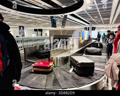 Dublin, Irlande - 21 octobre 2025 : les bagages se déplacent sur un carrousel à bagages à l'aéroport de Dublin pendant que les voyageurs attendent. Banque D'Images
