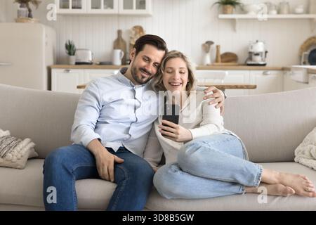 Couple aimant câlin sur canapé confortable prendre selfie à l'aide du téléphone Banque D'Images