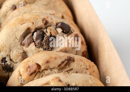 Gros plan extrême de biscuits texturés faits maison avec des morceaux de chocolat et des morceaux de noix dans une boîte. Concentrez-vous sur des ingrédients délicieux Banque D'Images