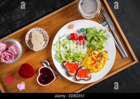 Petit déjeuner romantique. Saint Valentin. Omelette, sandwichs au caviar rouge et salade. Banque D'Images
