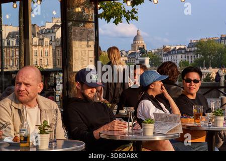 Paris, France - juin 2025 : les visiteurs apprécient les boissons et la conversation au Café des Arts sur les rives de la Seine à Paris. Le dôme du Panthéon Banque D'Images