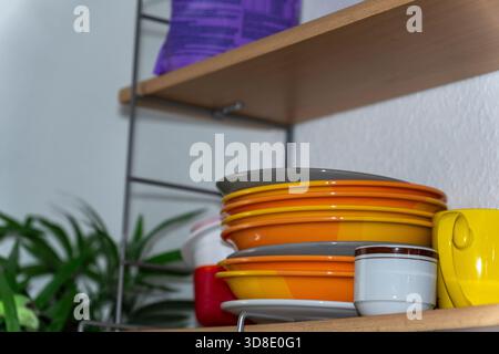 Une pile lumineuse de plats sur une étagère de cuisine ouverte. Banque D'Images
