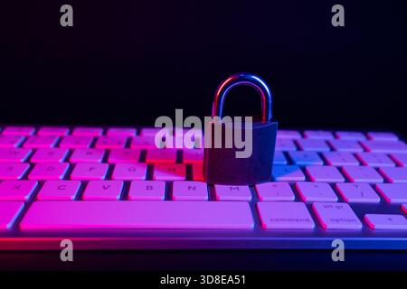 Un cadenas repose solidement sur un clavier, symbolisant la sécurité Internet. La scène présente des couleurs éclatantes et un faible éclairage, soulignant l'importance o Banque D'Images