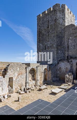 Vue verticale à l'intérieur des ruines du château de Palmela, Portugal. Un grand donjon médiéval en pierre surplombe d'anciennes arches et murs. Caillebotis moderne sur le sol. Banque D'Images